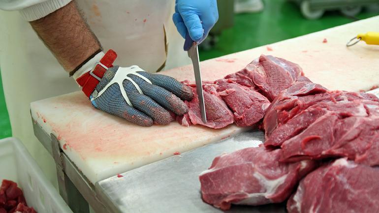 Butcher Cutting Pork Meat into Pieces for a Meat Market. Fresh raw pork chops in meat factory. Meat processing in food industry.